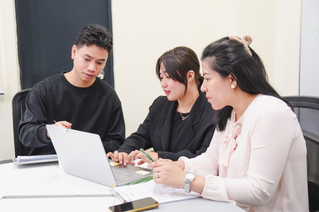 A group of three VizServe members in business casual clothing working together in an office.